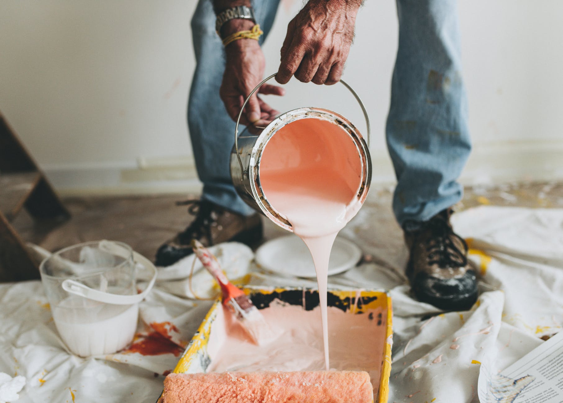 person holding pink paint bucket pouring on black container