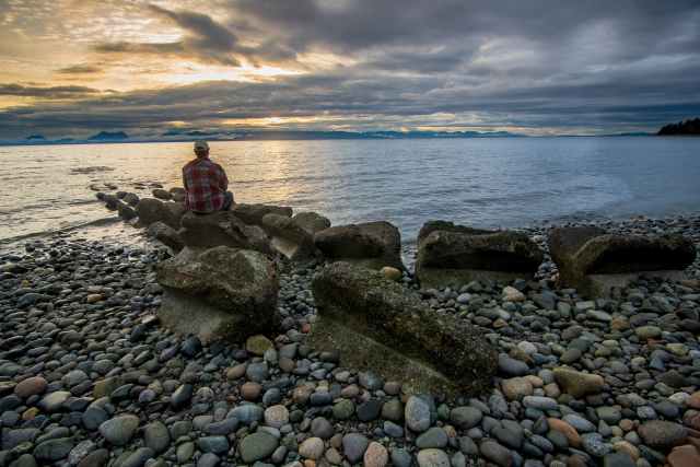 man sitting on a big rock